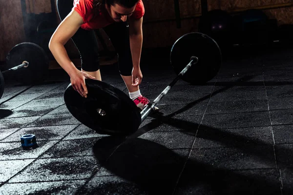 Mujer en gimnasio cambiando pesas en la barra de elevación — Foto de Stock