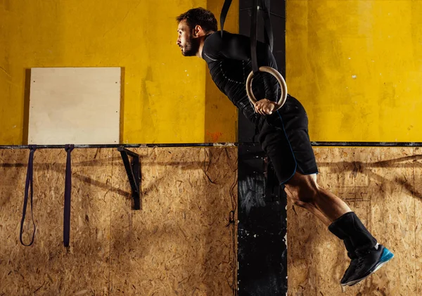 Músculo ups anéis homem balançando exercício na academia — Fotografia de Stock