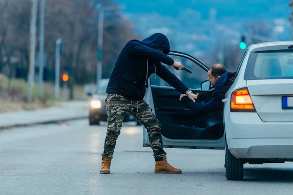 El ladrón de coches está sacando al dueño del coche de su coche y tratando de —  Fotos de Stock