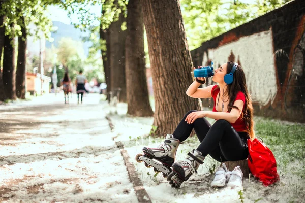 ローラーブレード運動後に水を飲む若い女性 — ストック写真