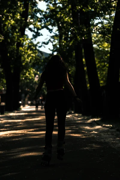 Sporty silhouette woman with inline skates riding through the pa — Stock Photo, Image