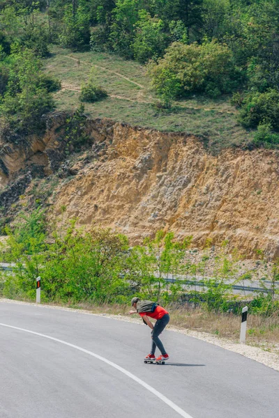 Männlicher kaukasischer Longboarder reitet auf einer leeren Straße bergab doin — Stockfoto