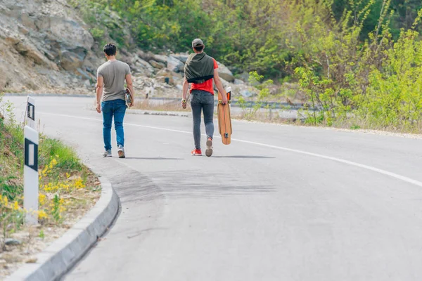 Two longboarders holding their longboards and walking downhill w — Stock Photo, Image