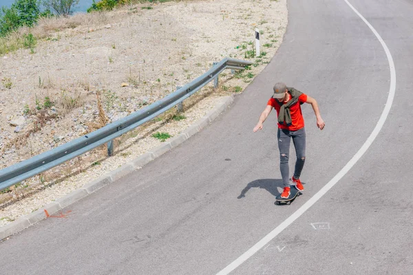Muž kavkazský longboardista sjíždějící z kopce po prázdné silnici, před — Stock fotografie