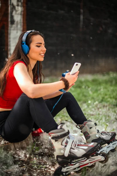 スマートフォンから青いヘッドフォンで音楽を聴く笑顔の女の子 — ストック写真