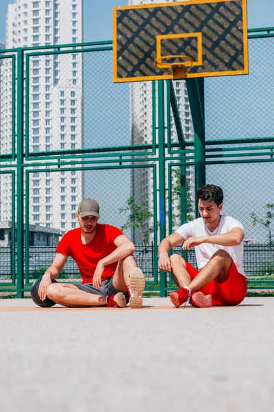 Dos jugadores de baloncesto descansando en la cancha a popa —  Fotos de Stock