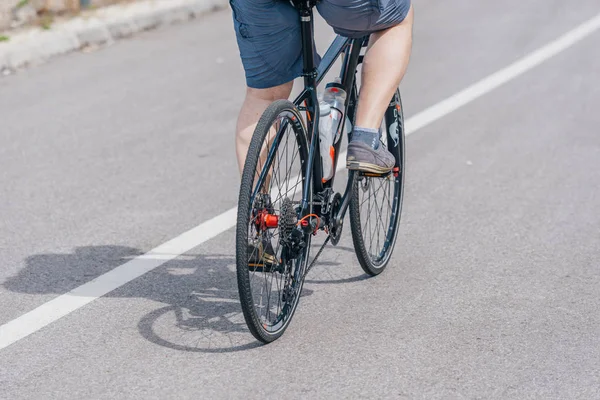 Un ciclista caucásico monta su bicicleta cuesta arriba, llevando profesión —  Fotos de Stock