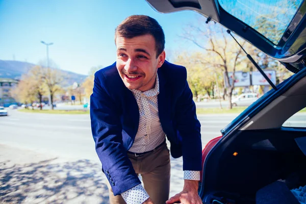Ein müder Geschäftsmann holt an einem sonnigen Tag einen Reifen aus seinem Auto — Stockfoto