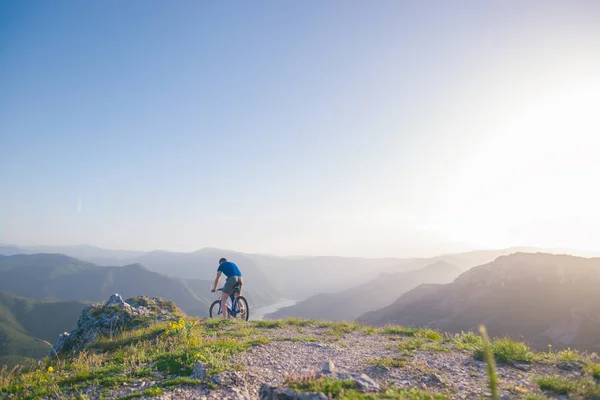 Mountainbiker houdt zijn fiets op een ruw klif terrein op een su — Stockfoto