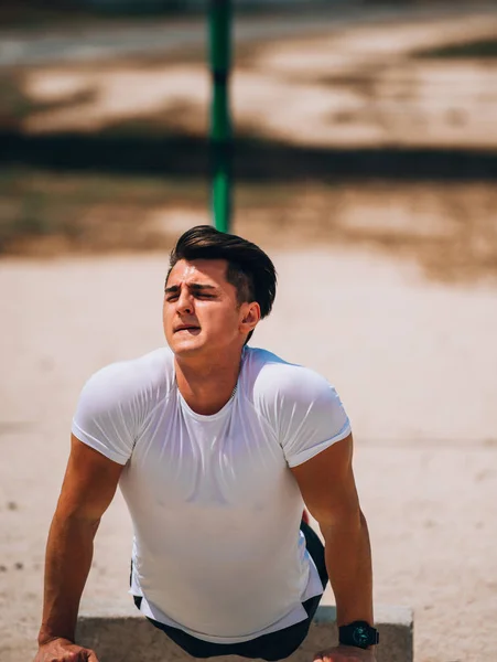 Jonge man doet push-ups op parallelle bars buitenshuis — Stockfoto