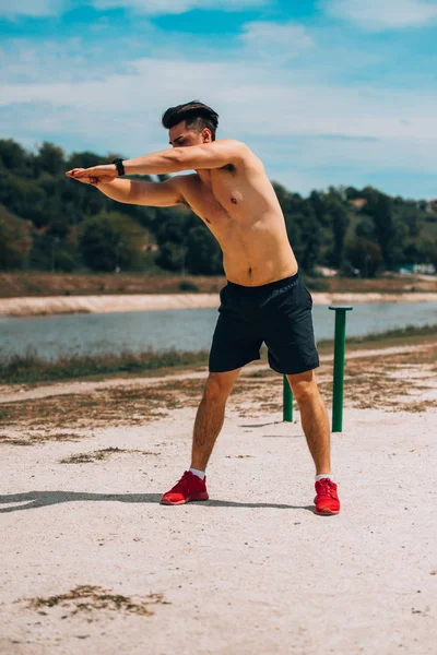 Fitness hombre sin camisa estirando los músculos de sus piernas al aire libre —  Fotos de Stock