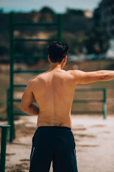 Deportivo atlético con cuerpo musculoso haciendo ejercicio sobre arena —  Fotos de Stock