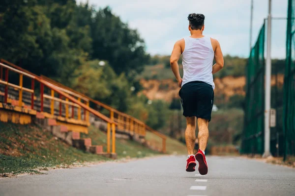 Atletische man joggen buiten, trainen buitenshuis. Draait op de weg — Stockfoto