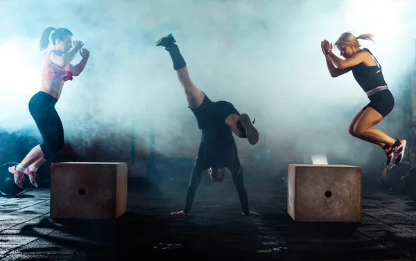 Tři sportovní lidé dělají skákací box v crossfit tělocvičně — Stock fotografie