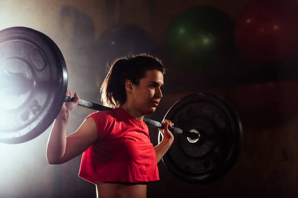Mujer atlética joven bombeando los músculos en el gimnasio crossfit — Foto de Stock