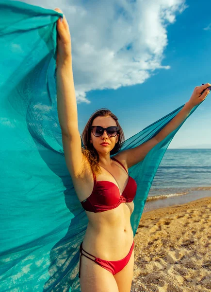 Beautiful young woman posing in red bikini at the beach — Stock Photo, Image