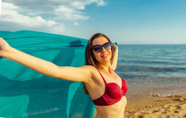 Young sexy woman in bikini holding scarf on sea background — Stock Photo, Image