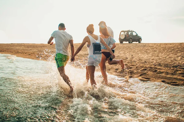 Ομάδα ευτυχισμένοι φίλοι τρέξιμο στο νερό το καλοκαίρι — Φωτογραφία Αρχείου
