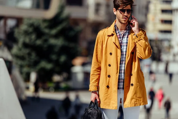 Bonito cara vestindo casaco amarelo falando no telefone — Fotografia de Stock