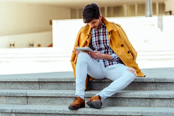 Stilvoller Mann in gelbem Mantel am urbanen Ort mit PC-Tablet — Stockfoto