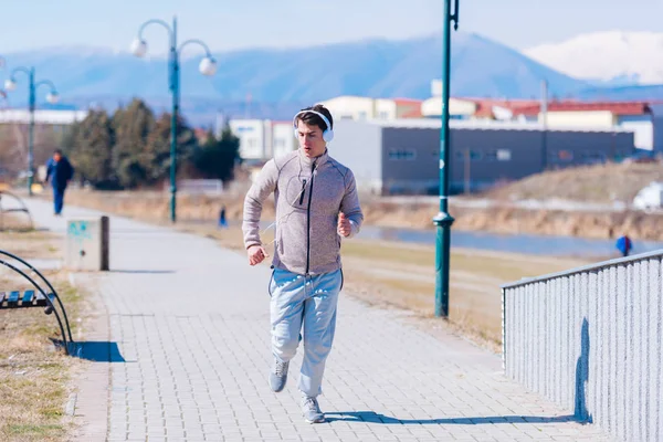 一名气喘吁吁的运动员戴着头电话在赛道上跑得很快 — 图库照片