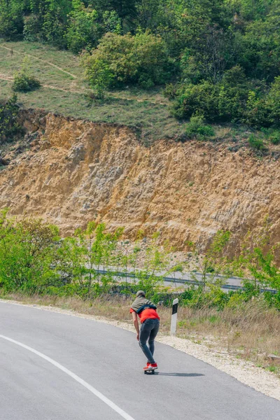 Männlicher kaukasischer Longboarder reitet auf einer leeren Straße bergab doin — Stockfoto