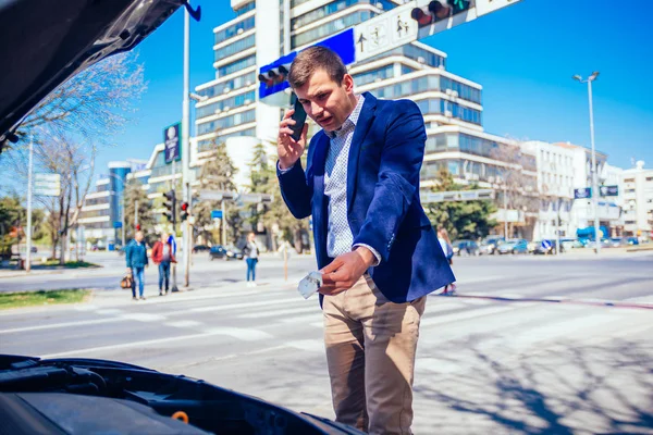 Jovem empresário está falando em seu telefone enquanto olha sob th — Fotografia de Stock