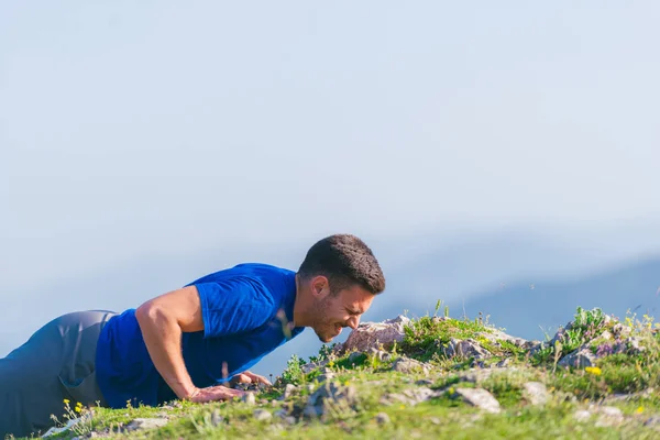 Un giovane atleta maschio in forma sta facendo flessioni all'aperto su una scogliera w — Foto Stock