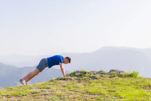 Egy fiatal Fit férfi sportoló csinál push-up szabadban egy sziklán w — Stock Fotó