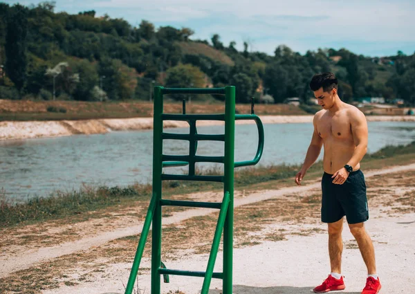 Fitness homem sem camisa alongando seus músculos do corpo ao ar livre — Fotografia de Stock