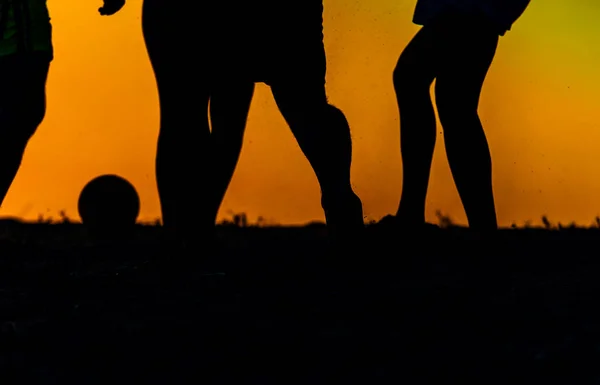 Amigos da silhueta jogando futebol — Fotografia de Stock