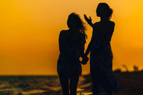 Détendez les filles en robe d'été debout sur la plage coucher de soleil — Photo