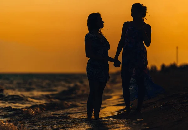 Silhouet van een meisjes tegen de zonsondergang aan zee — Stockfoto