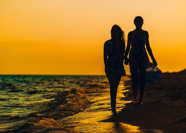 Silhouet ontspannen dames aan het strand in zonsondergang — Stockfoto