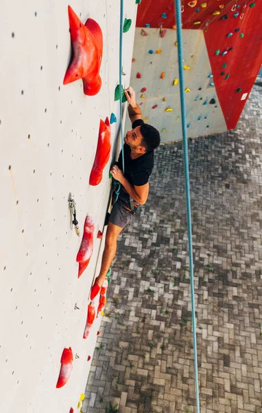 Спортивный человек взбирается на искусственную скальную стену — стоковое фото