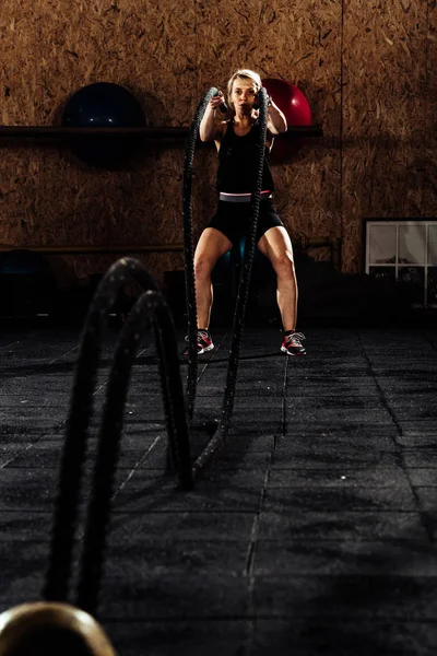 Mujer haciendo ejercicio con cuerdas de batalla en el centro crossfit — Foto de Stock