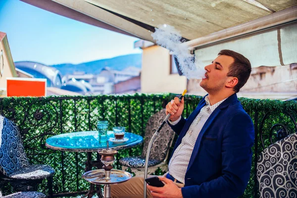 Молодой бизнесмен в пиджаке и хаки курит кальян на С — стоковое фото