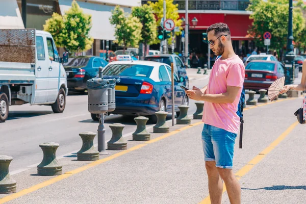 Estudiante llamando a un taxi mientras lleva una mochila en el hombro — Foto de Stock