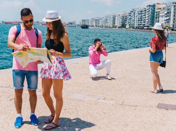 Una pareja está leyendo un mapa mientras que la otra está tomando fotos en —  Fotos de Stock