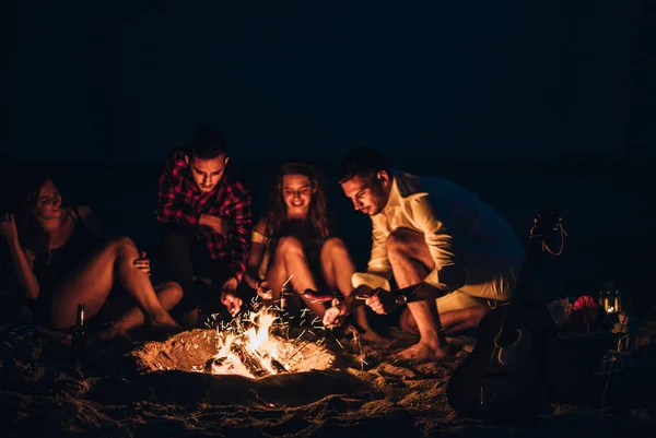 Campfire människor rostning korv och spela gitarr — Stockfoto