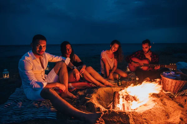 Campfire människor rostning korv och spela gitarr — Stockfoto