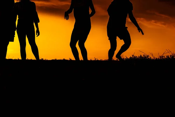 Groupe d'amis de la silhouette jouant au football sur une plage de sable fin à s — Photo