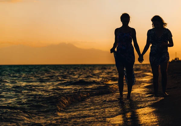 Silhouet van een twee fit vrouwen op het strand bij zonsondergang — Stockfoto