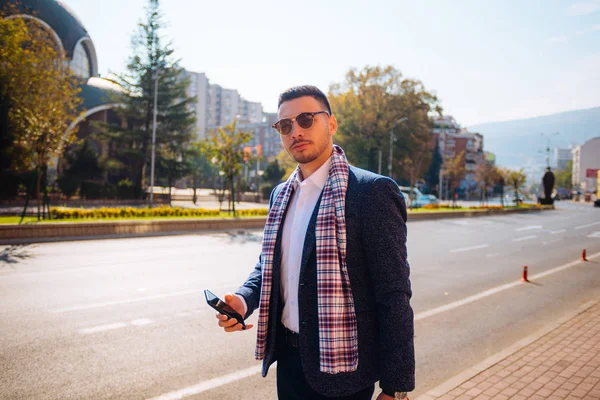 Jovem empresário descendo a avenida com seus óculos de sol — Fotografia de Stock