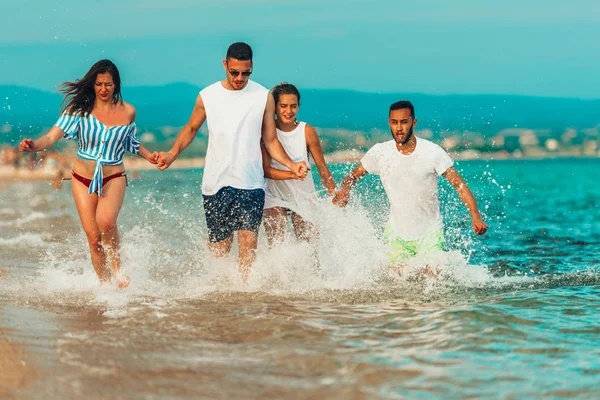 Grupo de amigos felices trotando en el agua en verano — Foto de Stock