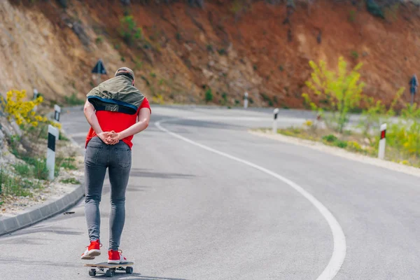 Alto atleta montando su longboard rápido y constante cuesta abajo mientras —  Fotos de Stock