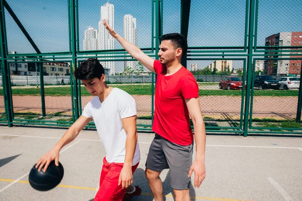 Dos jugadores de baloncesto machos fuertes juegan al aire libre peleando — Foto de Stock