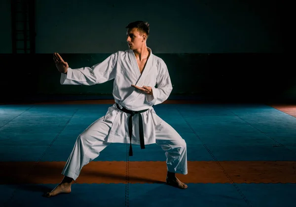 Ten chlápek z karate v bílém kimonu a černý opasek cvič karate — Stock fotografie