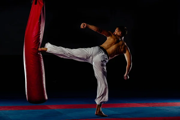Mužský boxer cvičí v tělocvičně s boxovací brašnou — Stock fotografie