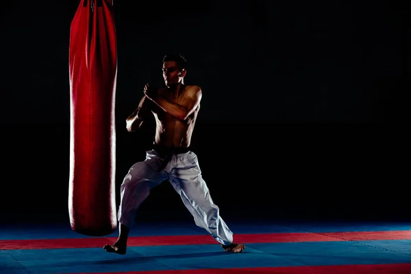Homem praticando boxe em grande saco preto no ginásio — Fotografia de Stock